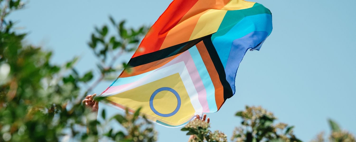 Drapeau Pride inclusif flottant dans le ciel, symbole de diversité LGBTQ+ et d’orientation sexuelle fluide.