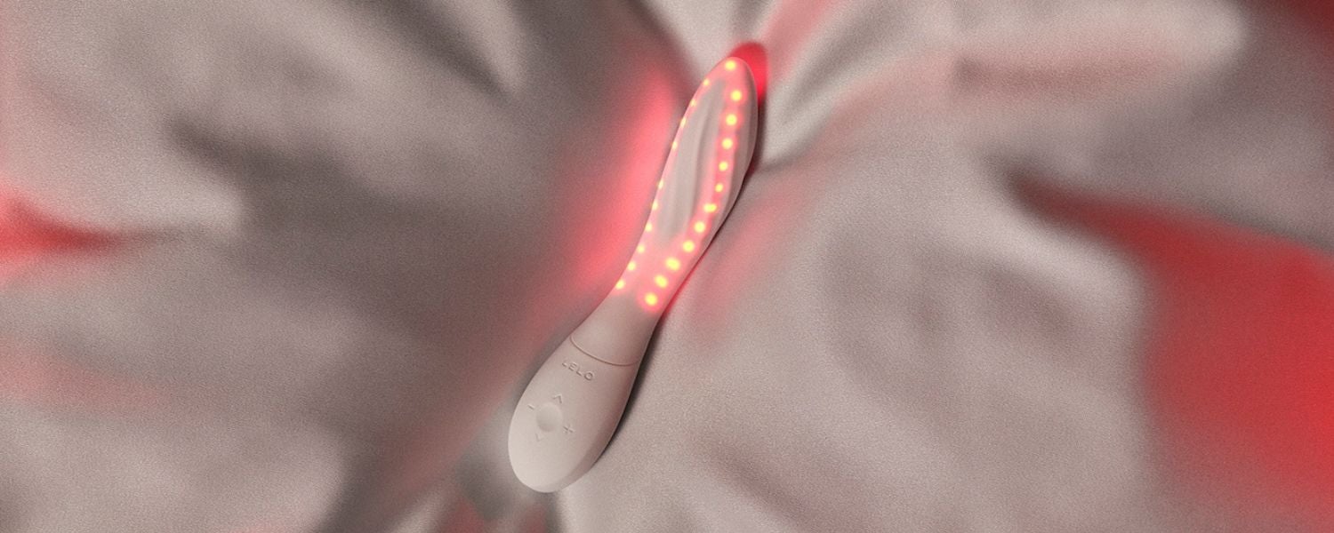 Lelo Mona Spectra auf weisser Bettwäsche in einem sanft beleuchteten Schlafzimmer mit sinnlicher Atmosphäre.