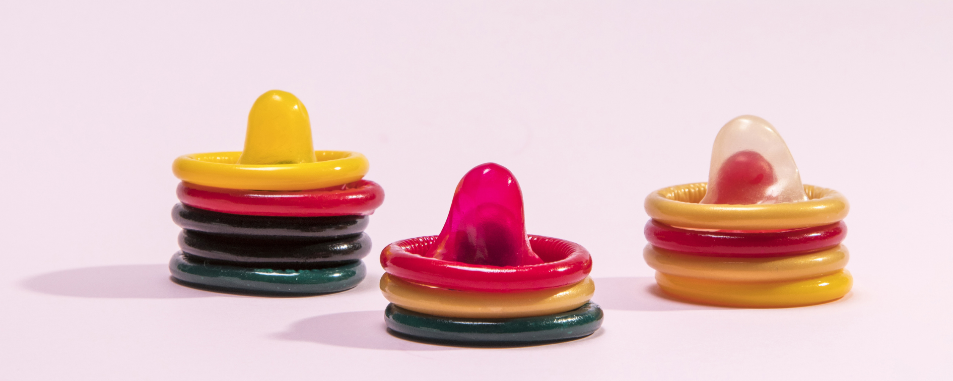 Verschiedene Kondome auf pinkem Hintergrund