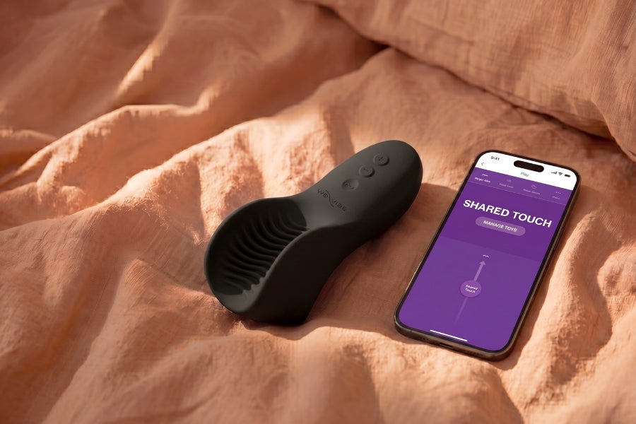 We-Vibe Shared Touch: App-gesteuerter Paarvibrator für gemeinsame Momente We-Vibe Shared Touch Paarvibrator mit Smartphone-App auf weicher Bettwäsche