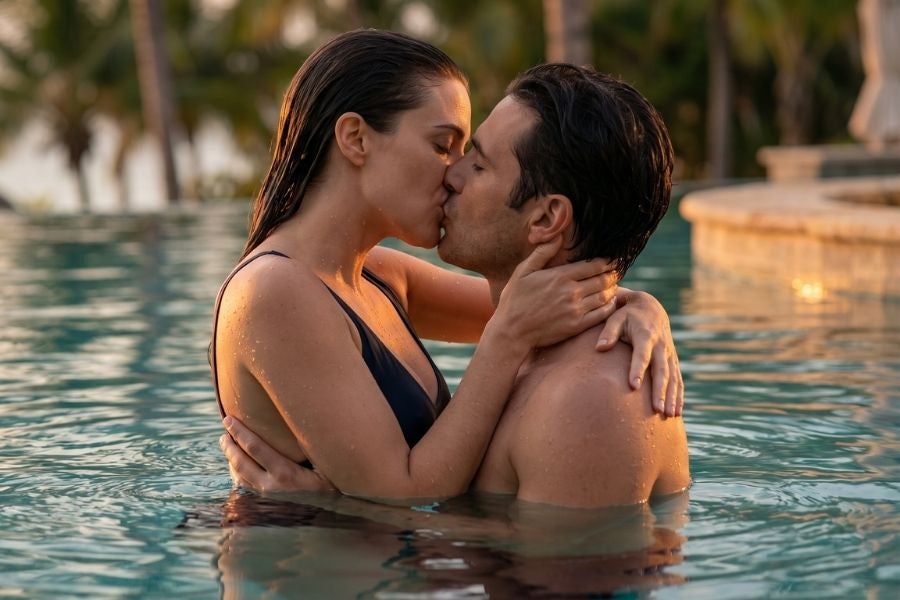 Leidenschaftlicher Kuss im Pool während einer heissen Sommernacht Paar küsst sich leidenschaftlich in einem tropischen Hotelpool bei Sonnenuntergang