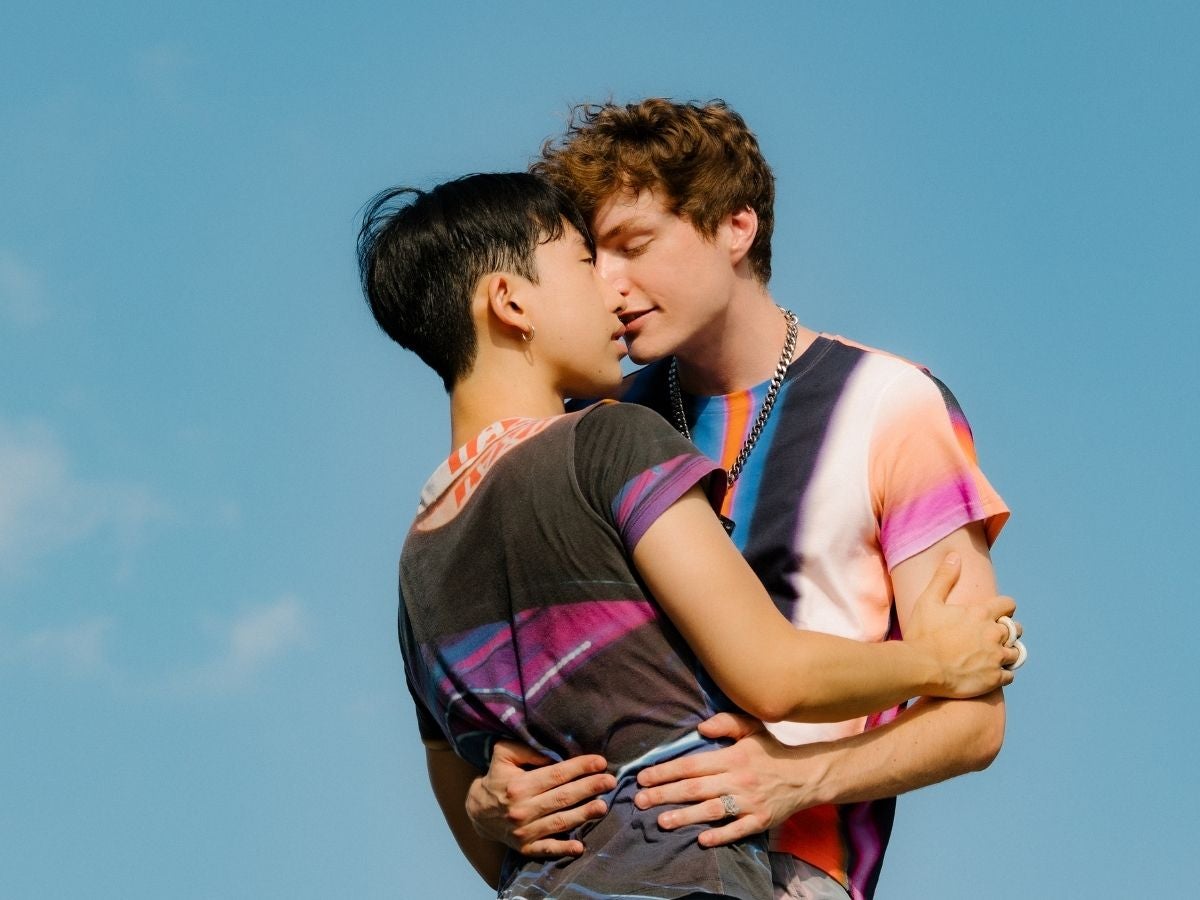 Liebe und Partnerschaft jenseits gesellschaftlicher Normen Zwei Personen umarmen sich vor blauem Himmel und stehen einander nah. Das Bild symbolisiert Liebe, Partnerschaft und Vielfalt.