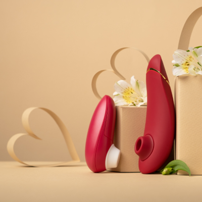 Ein roter Womanizer Premium 2 und Starlet 3 mit Papierherzen und weißen Blumen